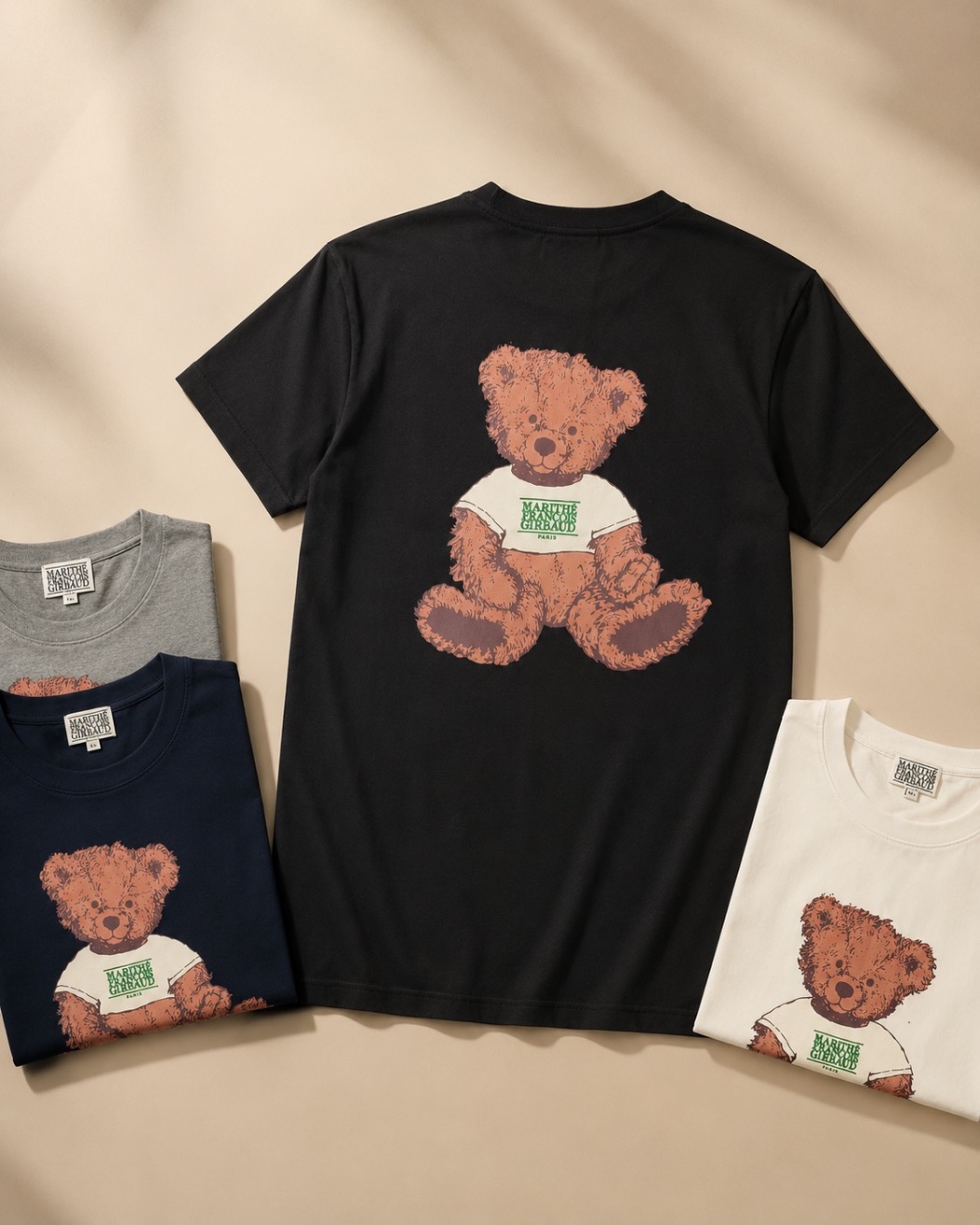 Black cotton tee with a printed graphic, shown across multiple folded colourways
